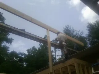 Carpenter setting a ridge beam over a new addition frame — Ice Dam Removal by Roofing Brothers in Tonica