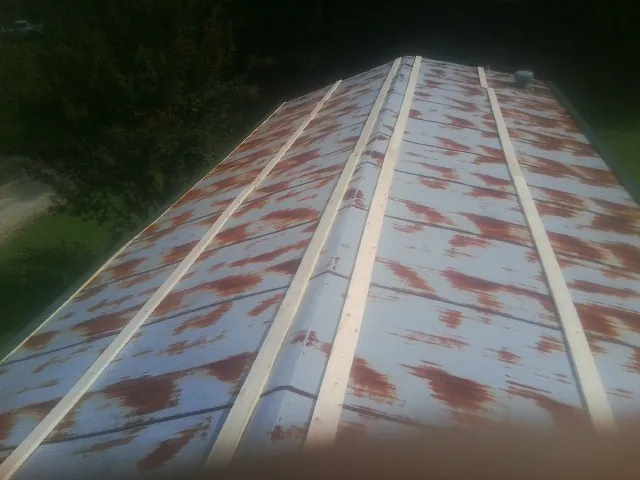 Rusted metal roof panels with new wood purlins before replacement — Storm Damage Roof Repair in Tonica by Roofing Brothers