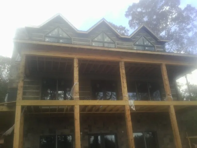 Dormers and porch framing on a large log home under construction — Roof Coating work by our crew in Tonica