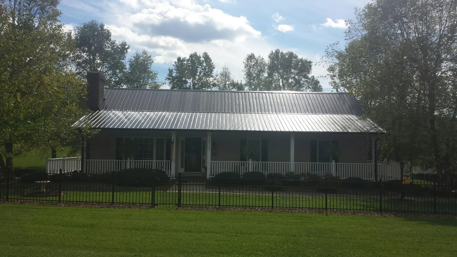 Gray metal roof on a brick ranch with a full width front porch — Gutter Guard Installation work by our crew in Tonica