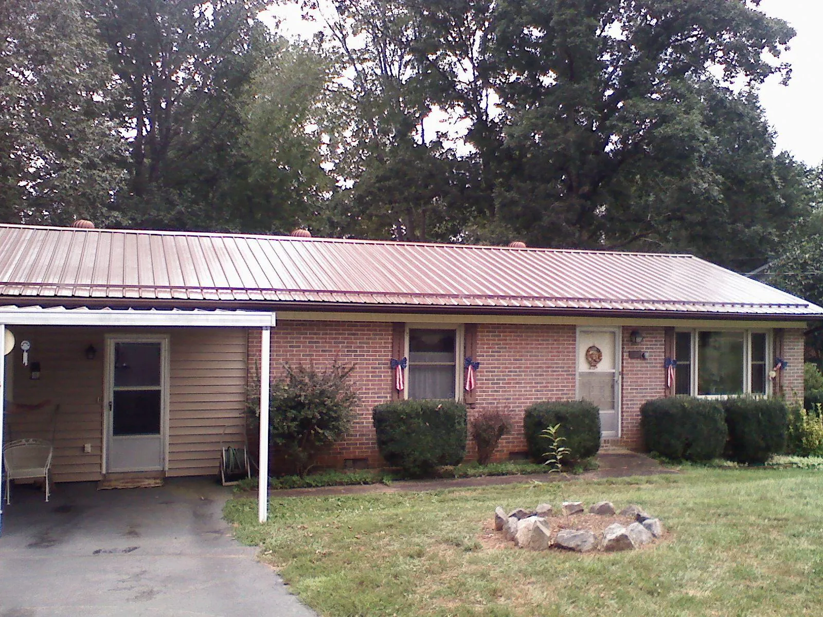 Bronze metal roof and carport on a brick ranch home — Roof Repair work by our crew in Tonica