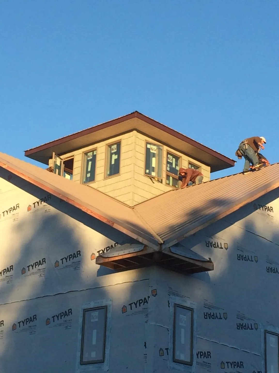Roofers working around a rooftop cupola on a new metal roof at sunset — Roof Waterproofing in Tonica by Roofing Brothers